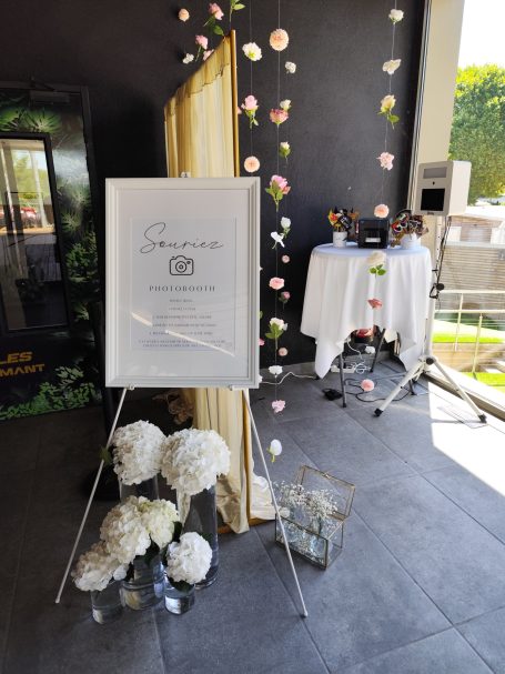 Décor d'événement avec un panneau, des fleurs et une table élégante.