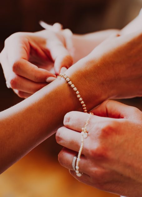Bracelet being fastened on a wrist by another person's hand.