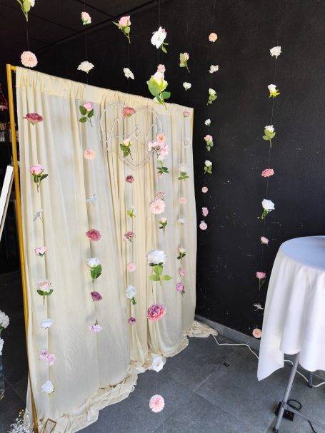 Décor floral avec des drapés beige et des fleurs suspendues sur un fond noir.