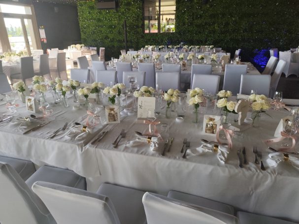 Table de réception élégamment décorée avec des fleurs blanches et des assiettes.