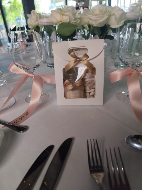 Table décor with a card, a figure, and elegant cutlery, adorned with roses.