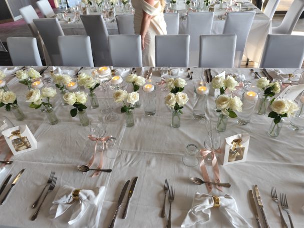 Tables dressées pour un événement, décorées de fleurs blanches et de bougies.