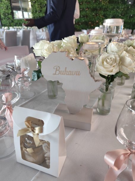 Décor de table avec fleurs blanches, marque-place et sachets cadeaux.