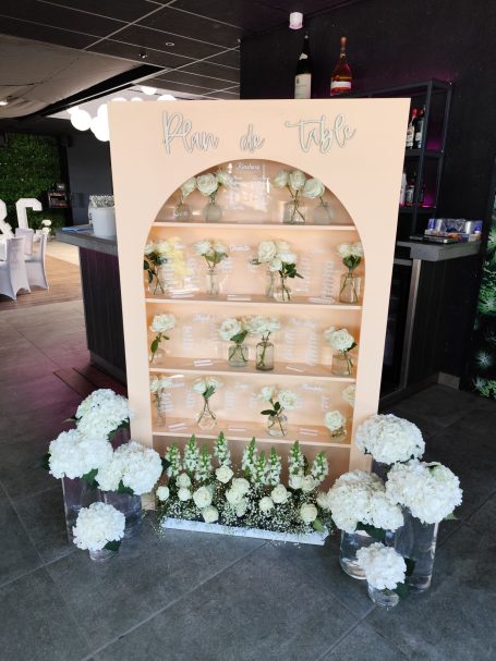 Un présentoir décoratif avec des fleurs blanches et vertes, sur fond sombre.