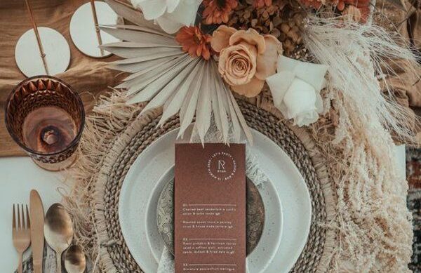 Tables dressées avec nappes blanches, décorées de fleurs et de petites bougies.