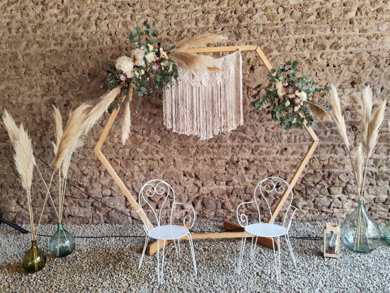 Décor de mariage en plein air avec une arche florale et deux chaises blanches.