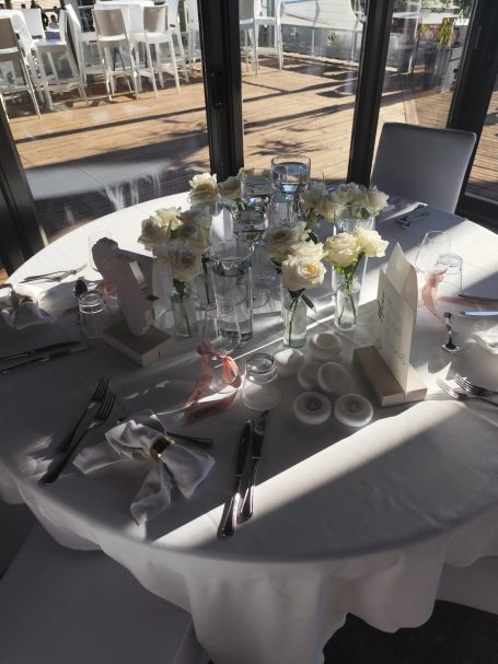 Table décor avec des roses blanches, des plats et des couverts élégants.