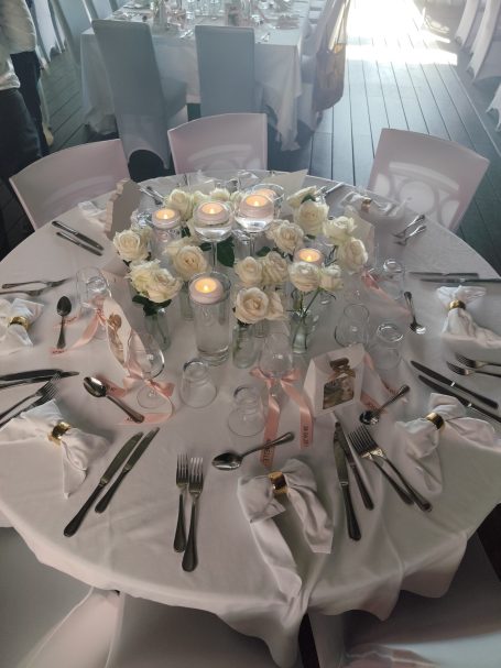 Table dressée pour un mariage, avec des roses blanches et des bougies.