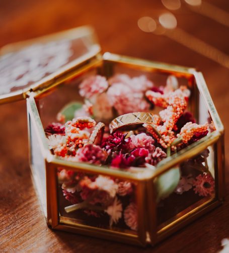 Boîte en verre contenant des fleurs séchées et une bague en métal.