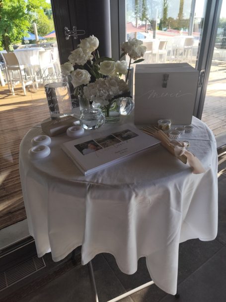Table dressée avec des roses blanches, une déco élégante et un livre d'invités.