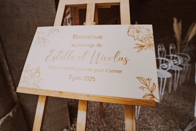 Panneau décoratif avec le nom "Estelle et Nicolas" et des motifs floraux.