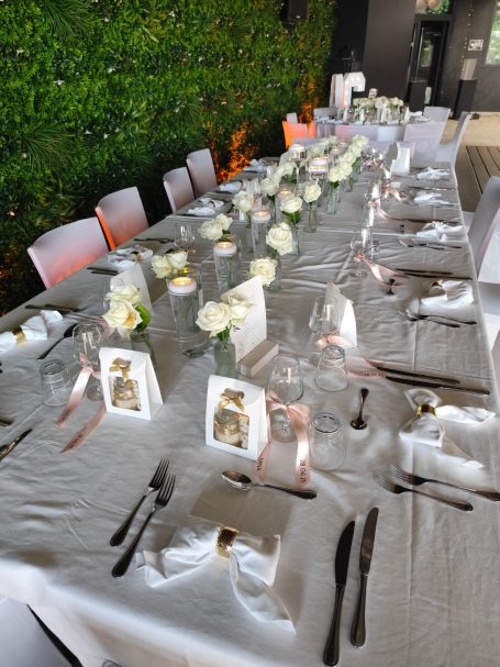 Table élégamment dressée avec des fleurs blanches et des accessoires de mariage.